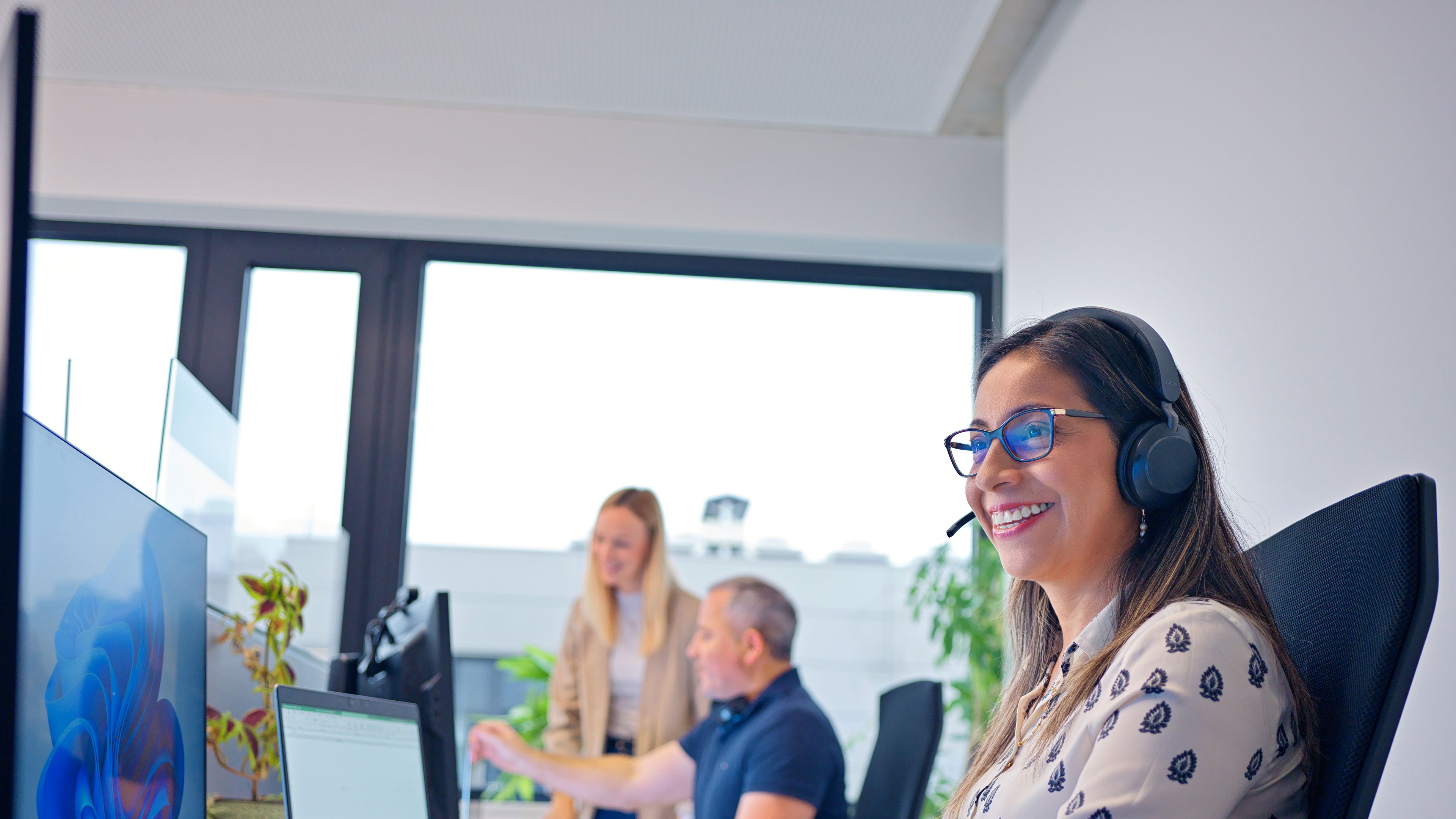 In an office, a lady from a call center sits in front of her computer.