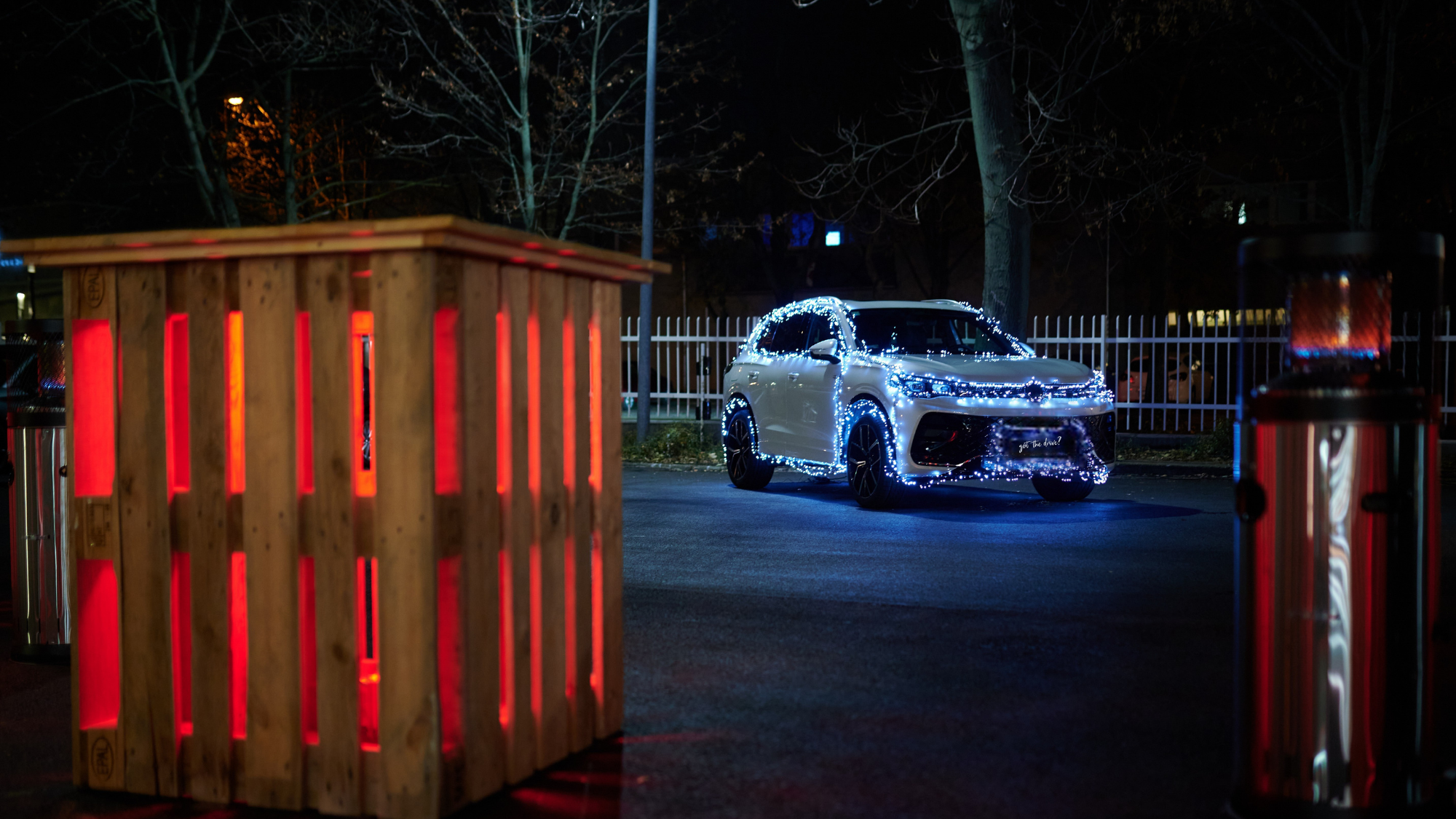 Autó fényfűzérrel, előtte egy kivilágított asztal és hősugárzó.