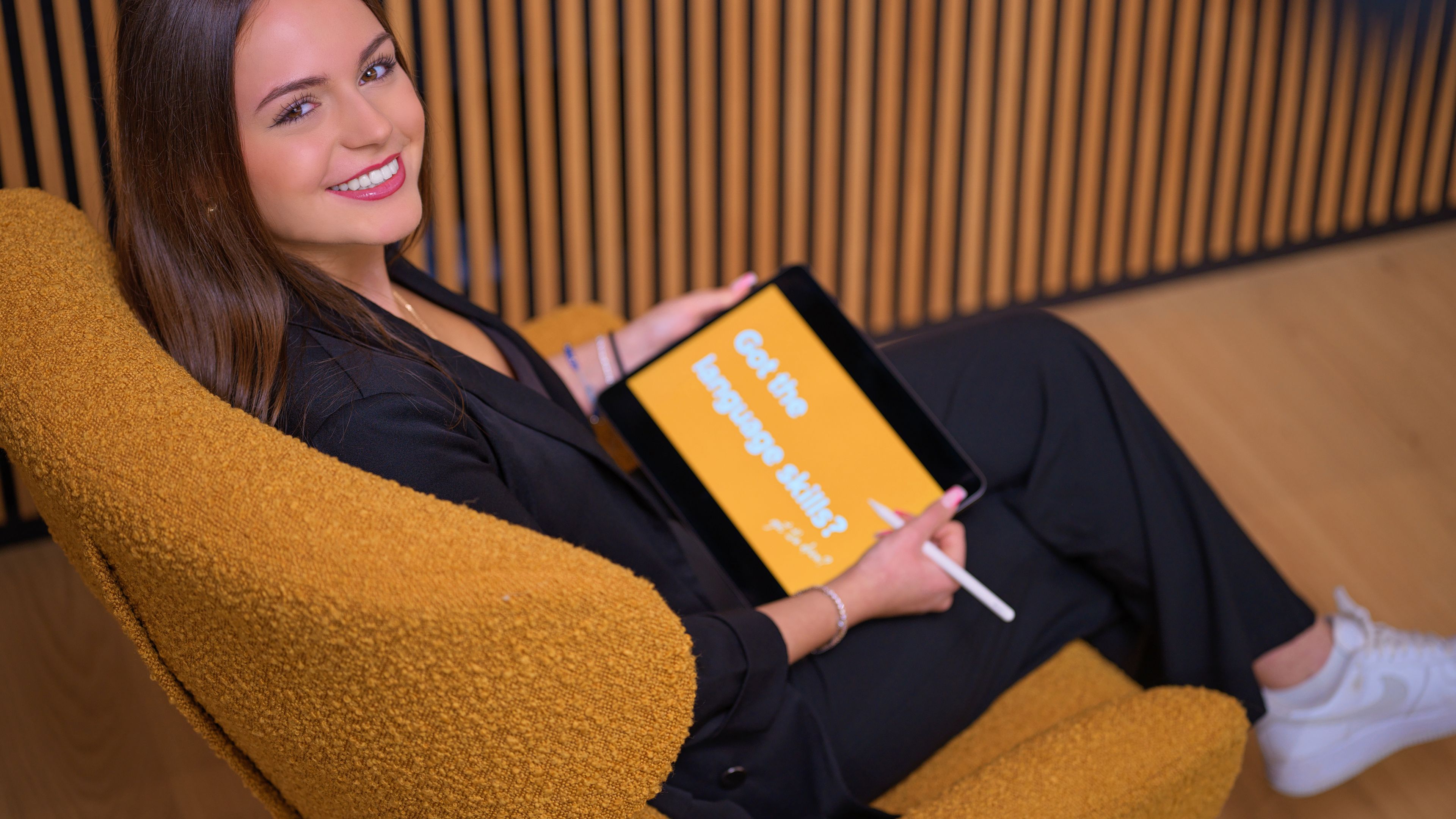 A young lady is smiling with a tablet in her hand.