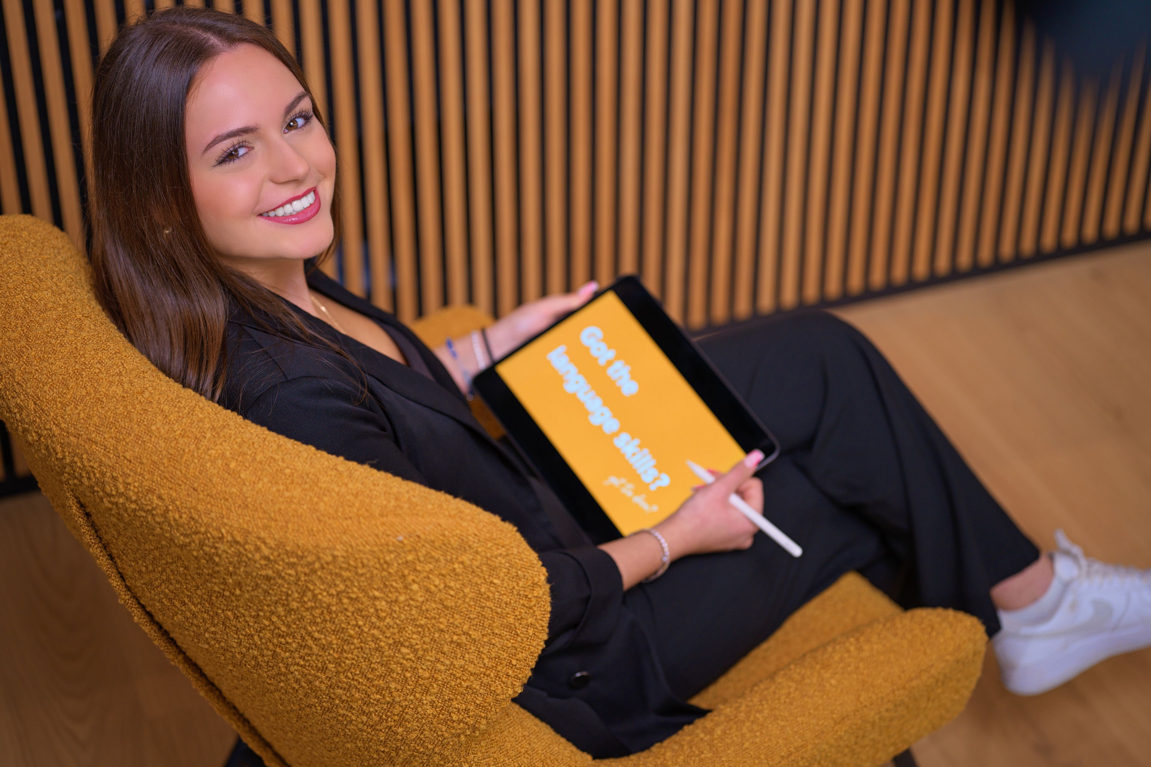 A young lady is smiling with a tablet in her hand.