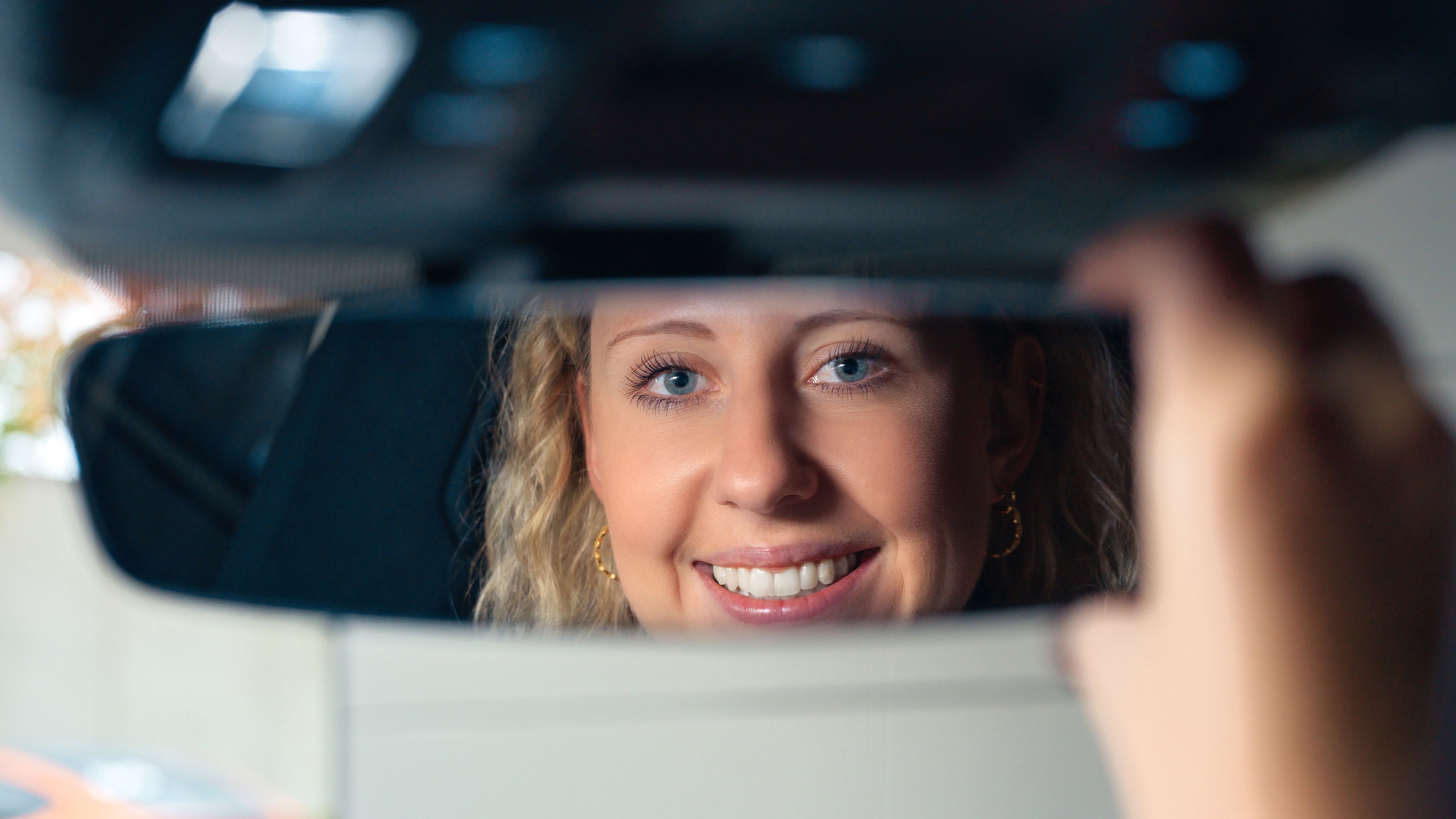 Egy hölgy megigazít egy visszapillantó tükröt.