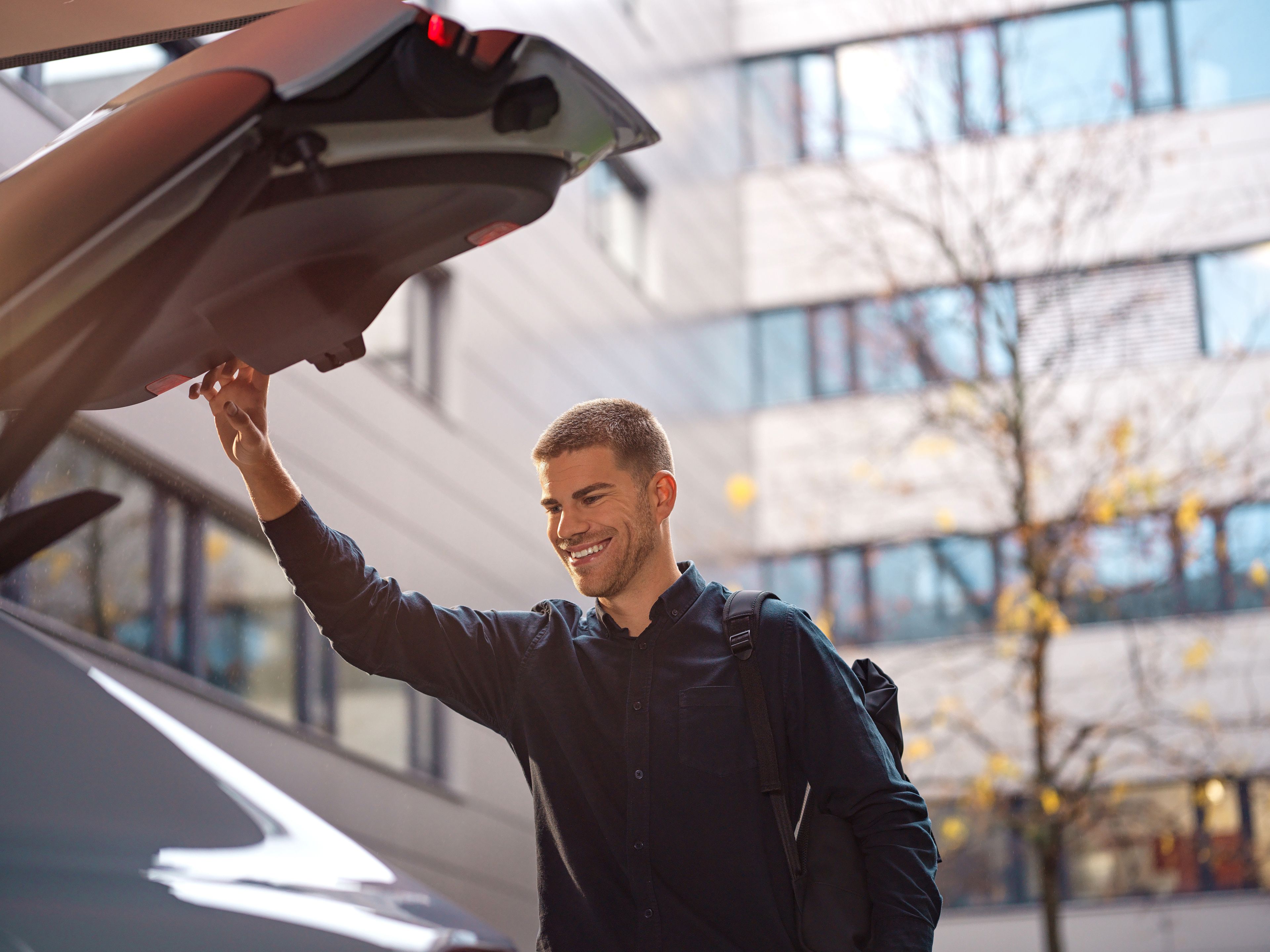 A man closes a trunk in the courtyard of an office.