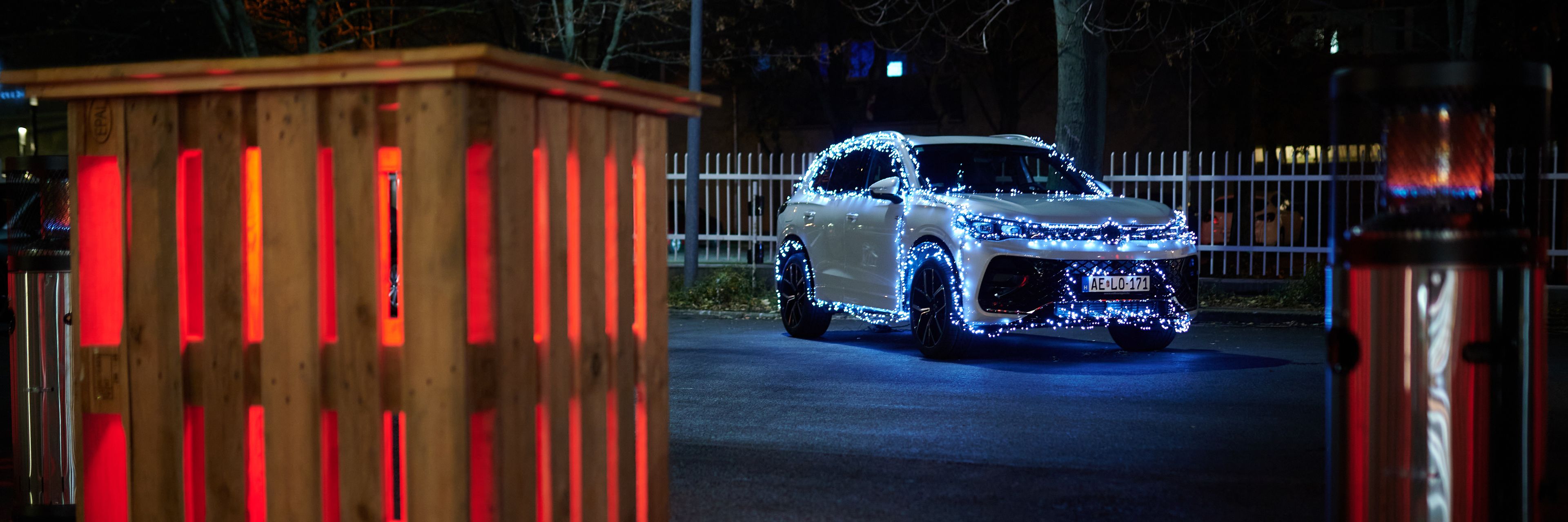 A car decorated with Christmas lights, an illuminated pallet table and a heater in front.