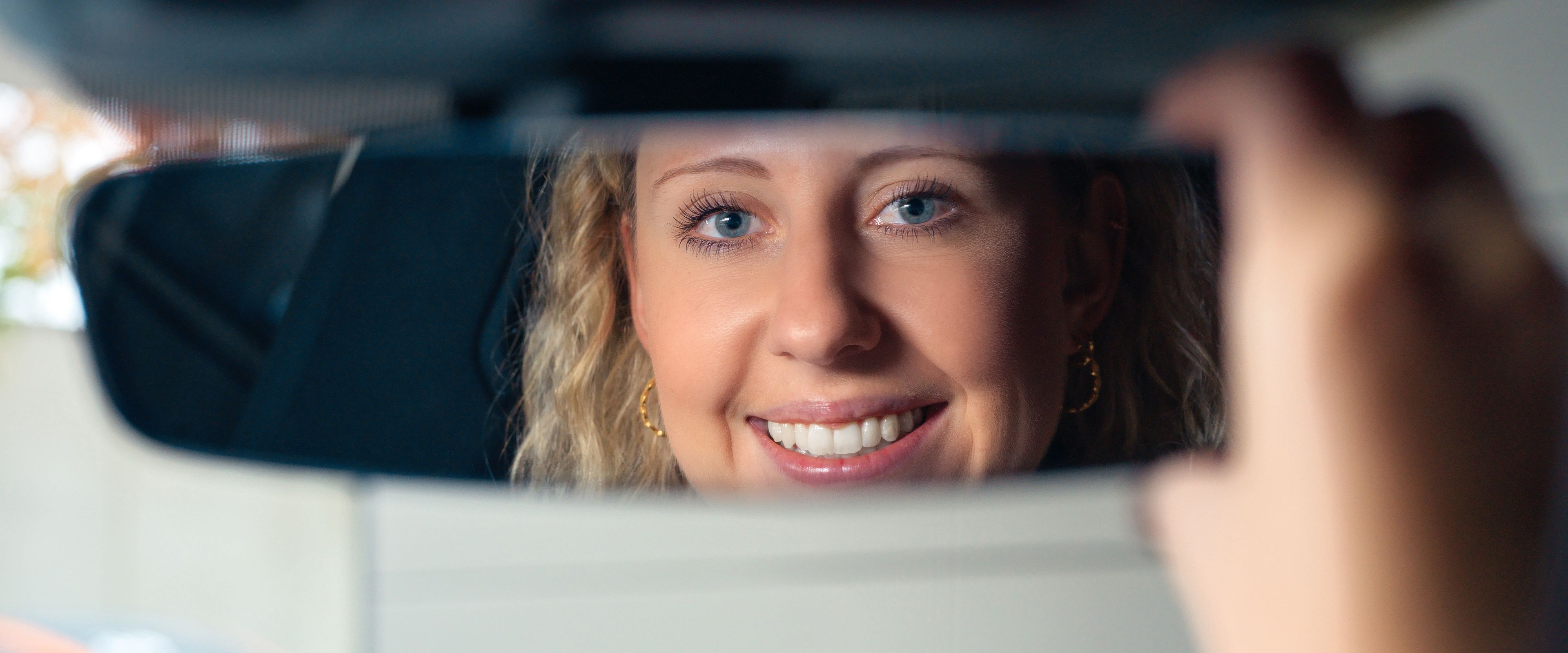 smiling woman in a rearview mirror