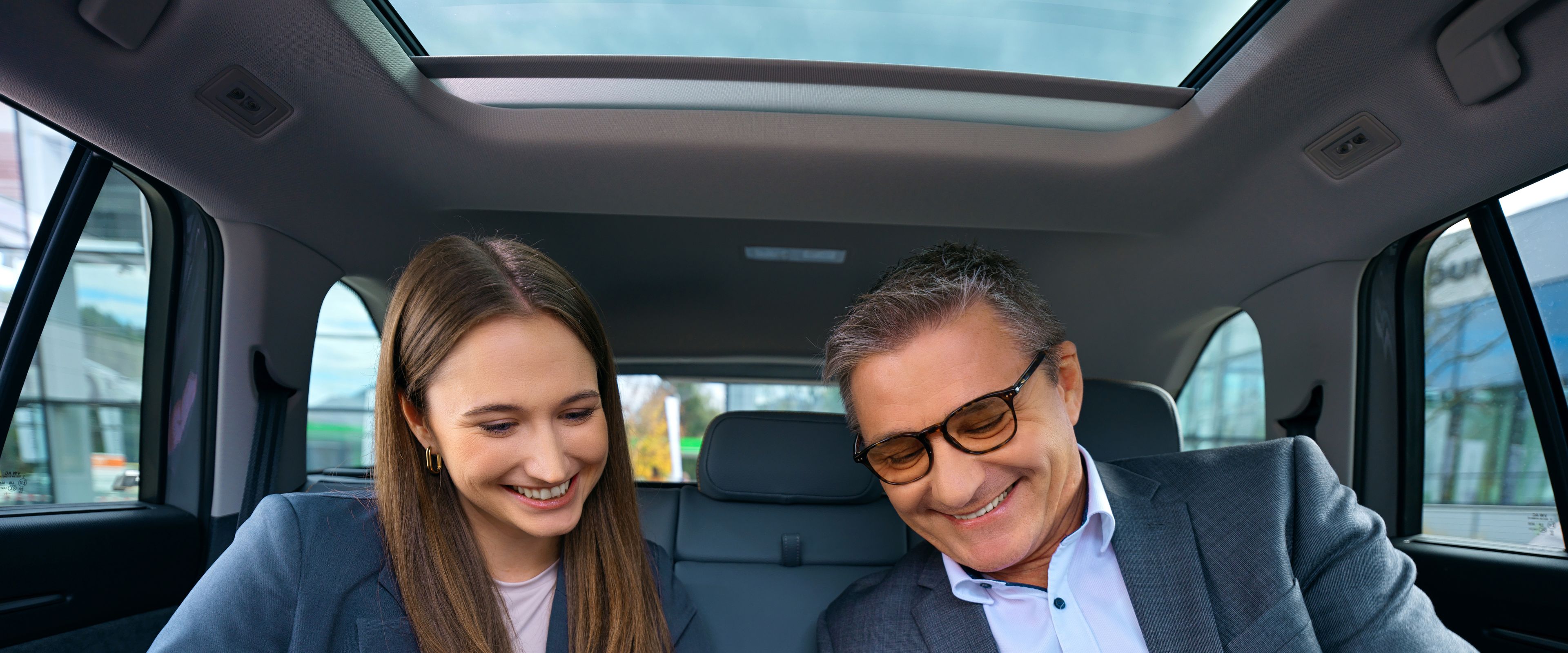 Two people sitting in a car and looking at a cell phone