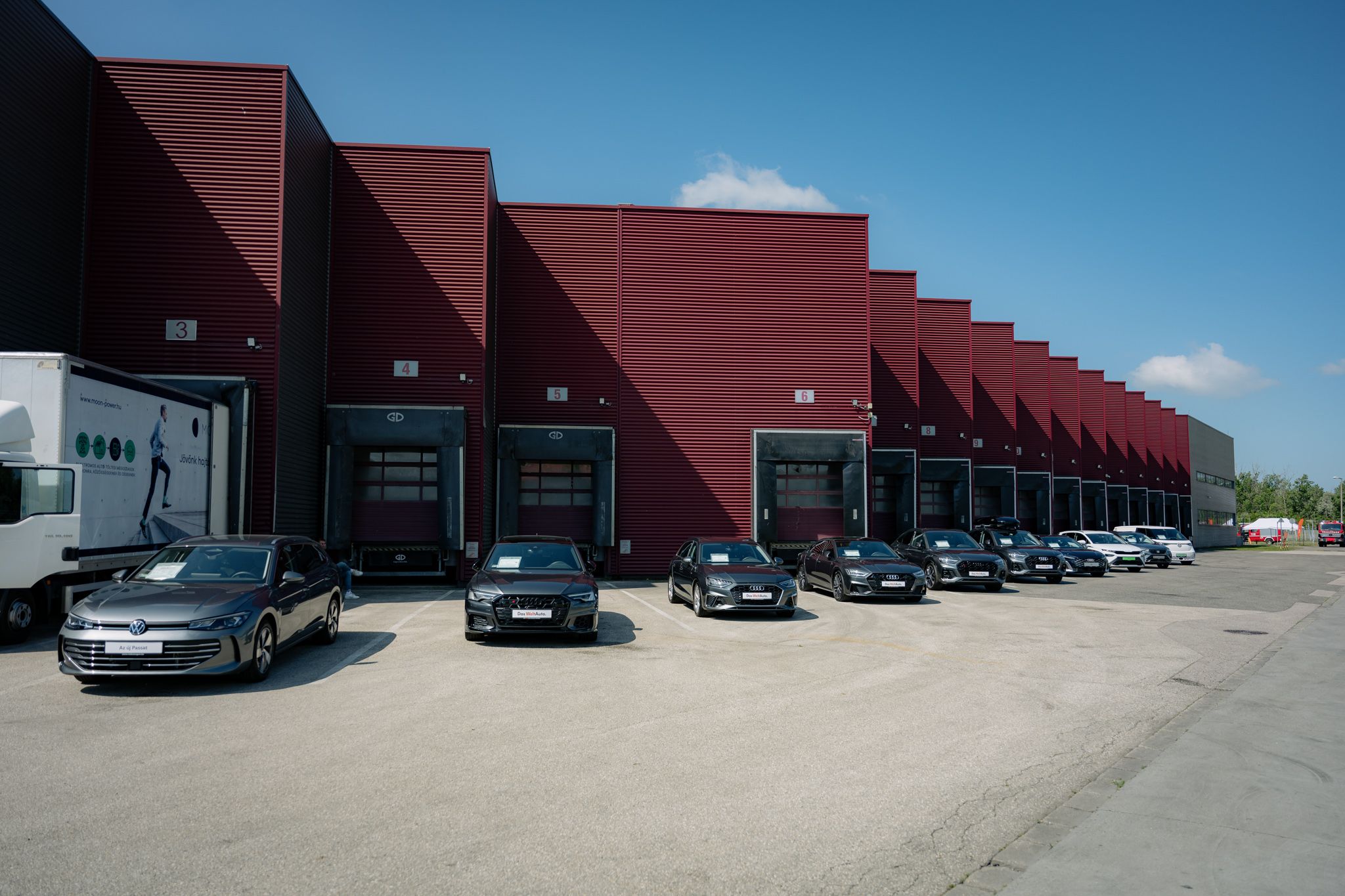 Cars park in front of a burgundy building.
