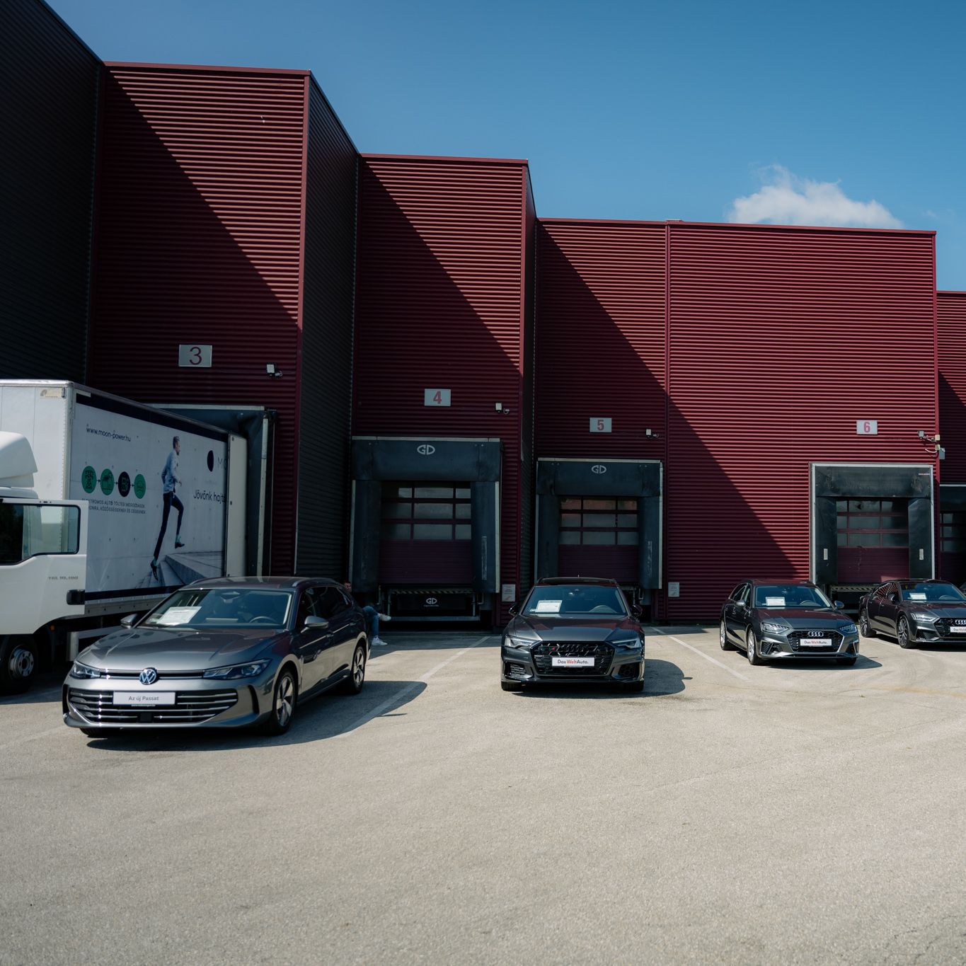 Cars park in front of a burgundy building.
