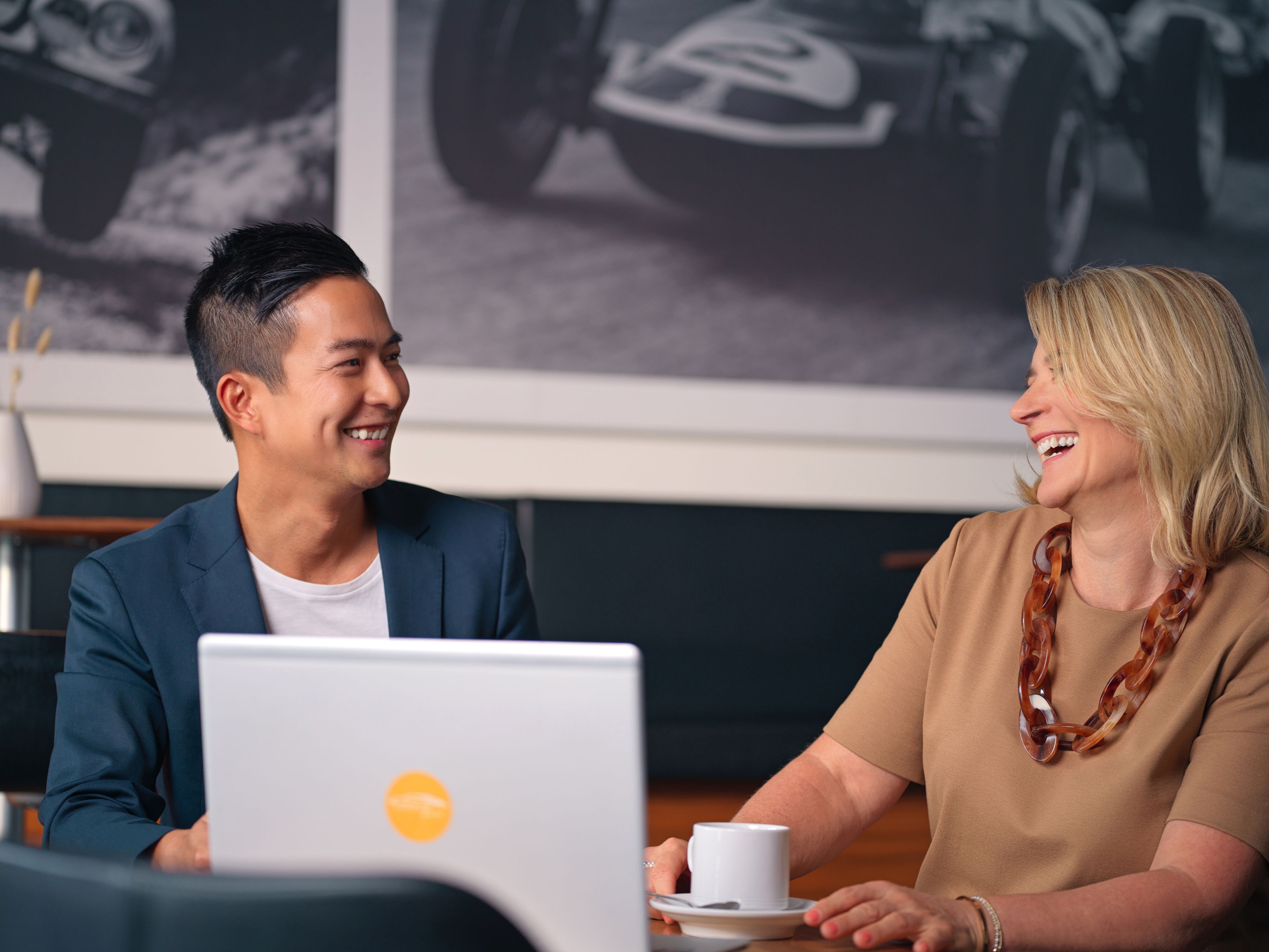 Two people sitting in a café, looking at a laptop