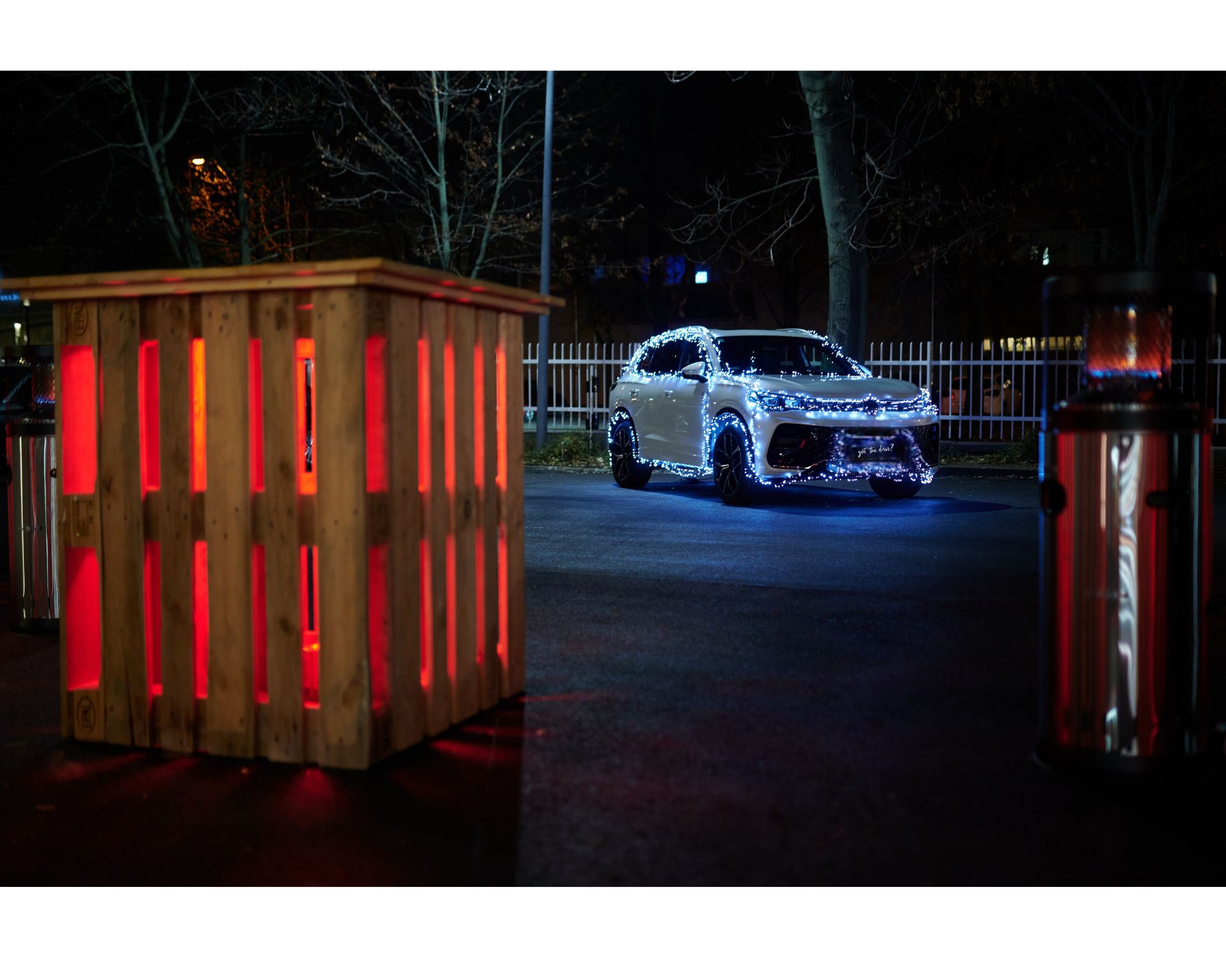 A car decorated with Christmas lights, an illuminated pallet table and a heater in front.