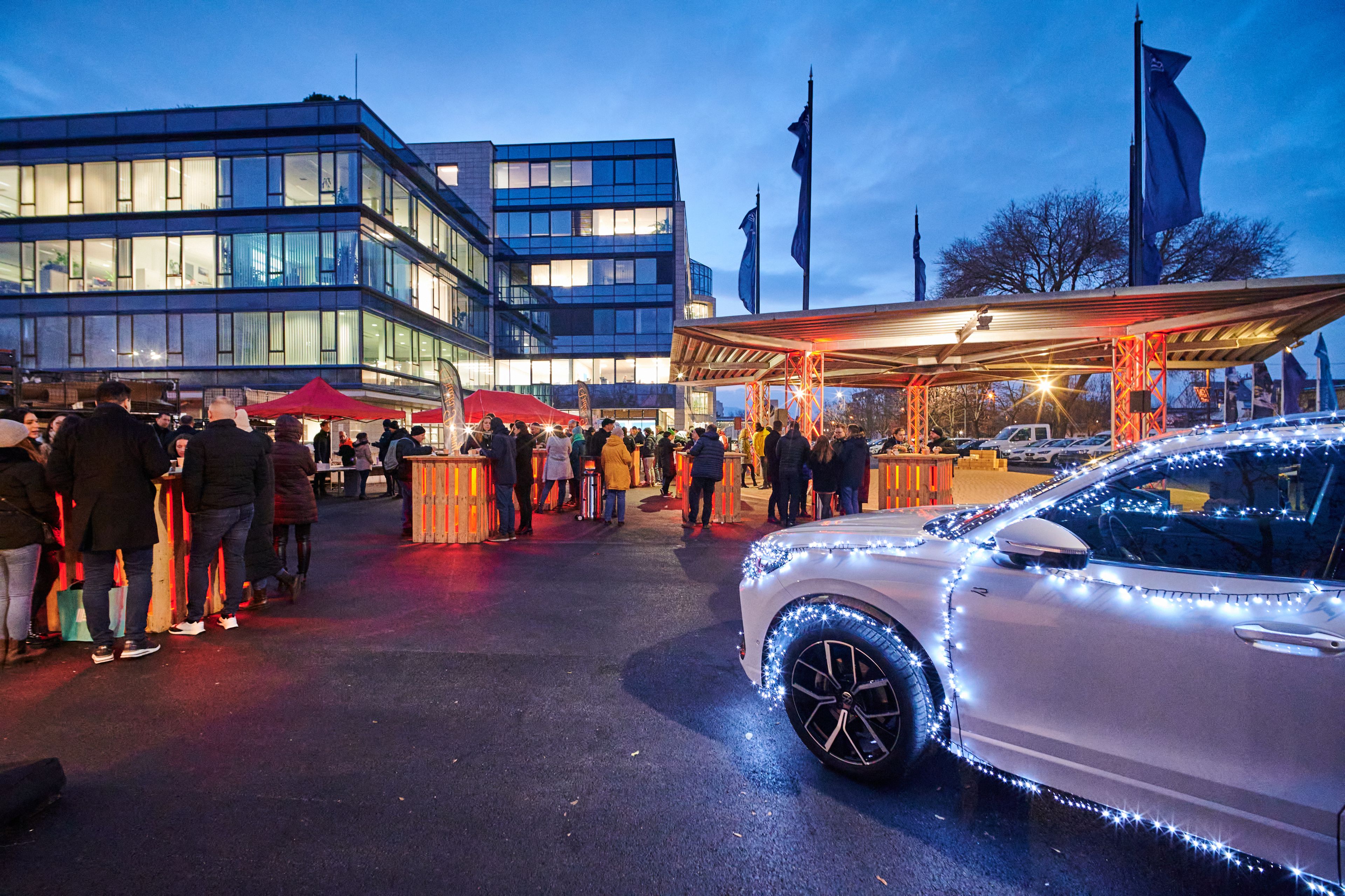Advent celebration next to the Porsche Hungaria building. Groups of people are celebrating and talking.